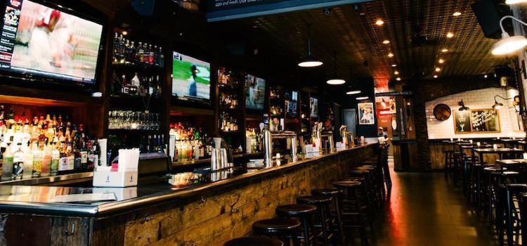 Image shows an extensive bar with several monitors mounted overhead, perfect for catching a football game. 