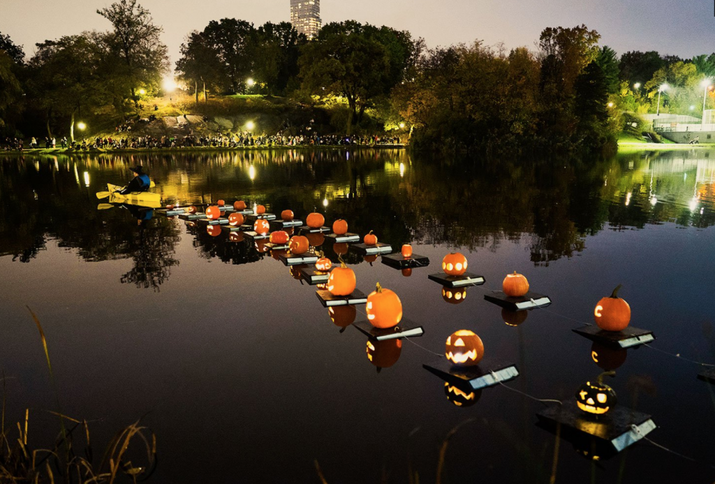 Image shows Pumpkin Flotilla, an annual tradition on the Harlem Meer, where individuals can drop of their carved pumpkins, to later be displayed in a floating train around the lake. 