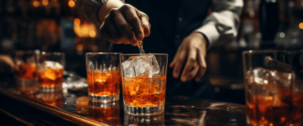 bartender stirring two glasses of whiskey with ice
