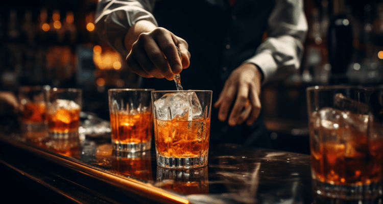bartender stirring two glasses of whiskey with ice