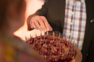 man grabbing a small wine sample from a tray platter