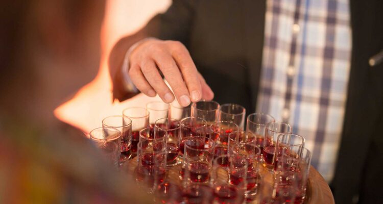 man grabbing a small wine sample from a tray platter